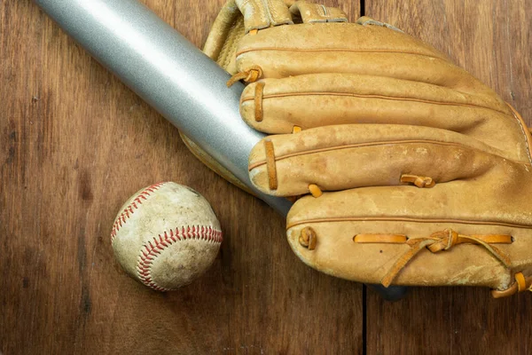 Vintage classic leather baseball glove and baseball bat isolated on wooden background.