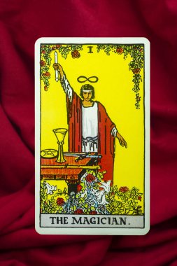 The Magician Tarot Card of Rider Waite deck on red fabric background. clipart