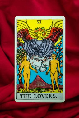 The Lovers Tarot Card of Rider Waite deck on red fabric background clipart