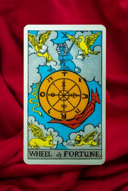 Wheel of Fortune Tarot Card of Rider Waite deck on red fabric background clipart