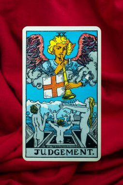 Judgement Tarot Card of Rider Waite deck on red fabric background clipart