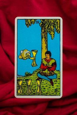 Yala Province, Thailand, June 1, 2022- Four of Cups Tarot Card of Rider Waite deck on red fabric background. clipart