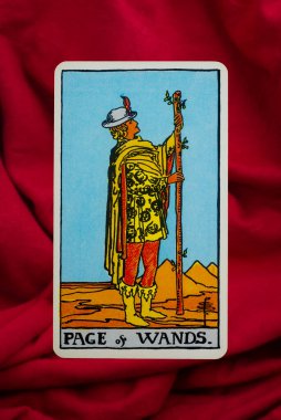 Yala Province, Thailand, June 1, 2022- Page of Wands Tarot Card of Rider Waite deck on red fabric background. clipart