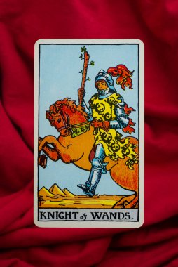 Yala Province, Thailand, June 1, 2022- Knight of Wands Tarot Card of Rider Waite deck on red fabric background. clipart