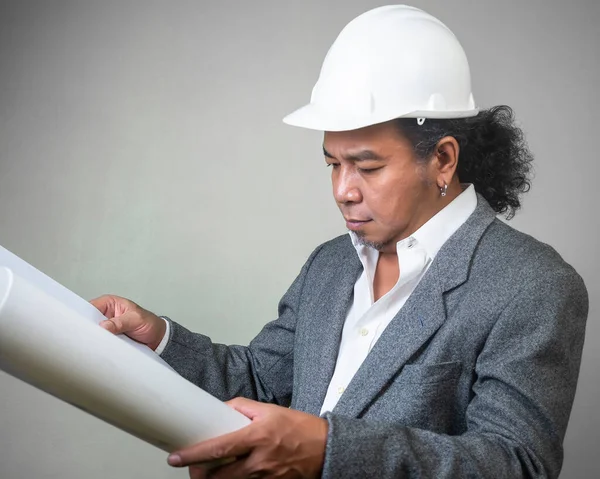 Engineer man worker with white safety uniform helmet  holding a drawing blueprint paper plan, construction process layout.