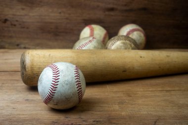 Close up old baseball and wooden baseball bat on a woodeb table. select focus.