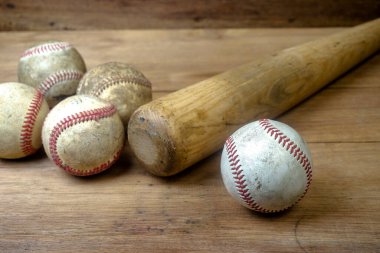 Close up old baseball and wooden baseball bat on a woodeb table. select focus.