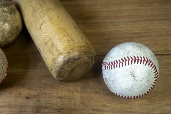 Close up old baseball and wooden baseball bat on a woodeb table. select focus.