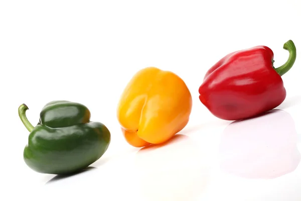 Zelené, červené a oranžové papriky na bílém pozadí — Stock fotografie