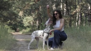 Bir kız ve bir köpek. Parkta evcil hayvanla neşeli bir yürüyüş. Ormandaki Dalmaçyalı.