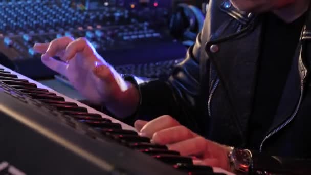 男性の手はピアノの電子キーボードで演奏。カラフルなステージ照明ドラムパッドミディコントローラーをタップする指。ホームレコーディングスタジオで楽曲制作を行うミュージシャン。サウンドメーカーは音楽のメロディーを作成. — ストック動画