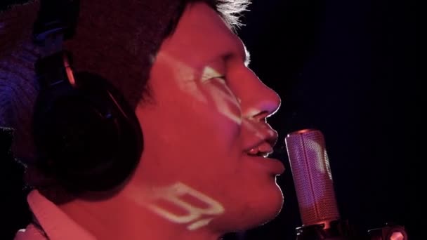 Közeli arc férfi énekes, énekes és mikrofon zenei koncerten a színpadi fény sugaraiban. — Stock videók