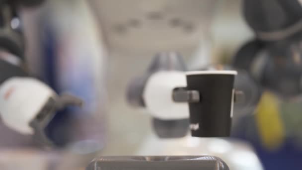 Motion of robotic arm making coffee. Robotic arm takes paper coffee cups. Mechanical robotic arm gives cup of coffee to a customer. — Stockvideo