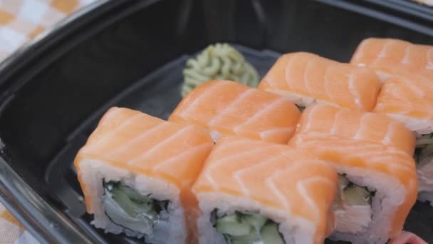 女の子は中華や日本料理店でロールと寿司を持っています。日本料理店でのランチ. — ストック動画
