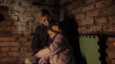 Ukrayna savaşı. Sığınak. Sığınak, Ukraynalı anne ve çocuk bodrumda. Savaş sırasında acı çekerek ve barış için dua ederek. Sığınma.