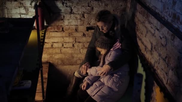 Guerra na Ucrânia. Fuga de civis. Abrigo anti-bombas. Família ucraniana senta-se em um abrigo anti-bomba. Bombardeio. Acção militar. Parem a guerra. Crise na Ucrânia, agressão, criança contra a guerra. — Vídeo de Stock