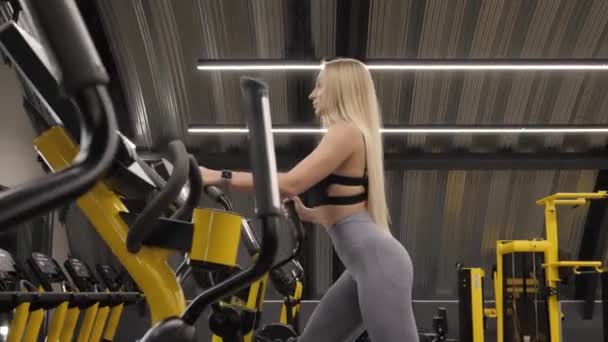 Trainen op een loopband. Fit vrouwen. Sporttrainingstoestellen in een fitnessruimte. Cardio routine op simulatoren. — Stockvideo