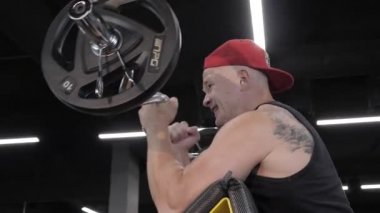 Vücut geliştirme. Adam ağırlık kaldırıyor. Fitness egzersizi. Spor kulübünde ağırlık kaldırıyorum. Güç, güç ve dayanıklılık egzersizleri halterle yapılır..