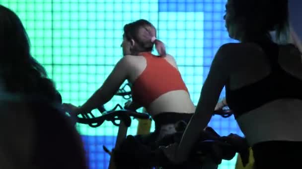 集体运动。适合女人。在固定自行车上训练。健身馆的运动训练设备。模拟器上的心血管例程。性感的女人. — 图库视频影像