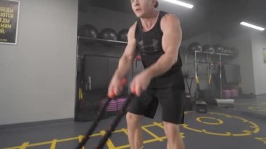 Spor salonunda erkek antrenmanı. Jimnastik. Savaş halatları kullanarak. Savaş halatlarıyla çapraz oturum..