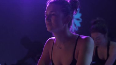 Simülatörlerde kardiyo rutini. Formda kadınlar. Sabit bisiklette antrenman yapıyorlar. Spor salonundaki spor malzemeleri..