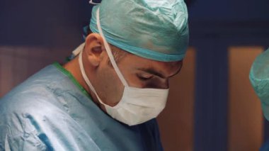Doctors face in a medical uniform and a mask makes an operation in the operating room. Helping a wounded man.