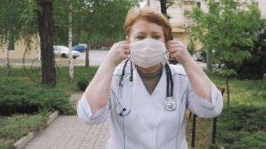 Hospital worker in scrubs putting medical mask on face. Health Protection Corona Virus.