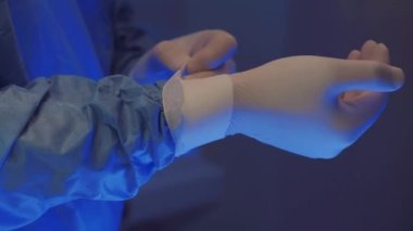 Doctors hands takes off medical gloves after surgery. The surgeon has finished his work.