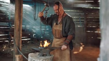Blacksmith in the forge forges a horseshoe. Blacksmith makes iron products. Flames of fire in the Forge workshop.