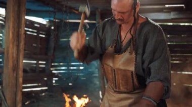 Blacksmith in the forge forges a horseshoe. Blacksmith makes iron products. Flames of fire in the Forge workshop.