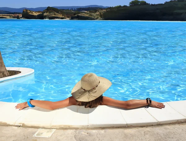 Ragazza bionda con berretto di paglia in piscina — Foto Stock