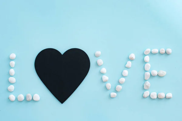 Word love on a blue background with white pebbles — Stock Photo, Image