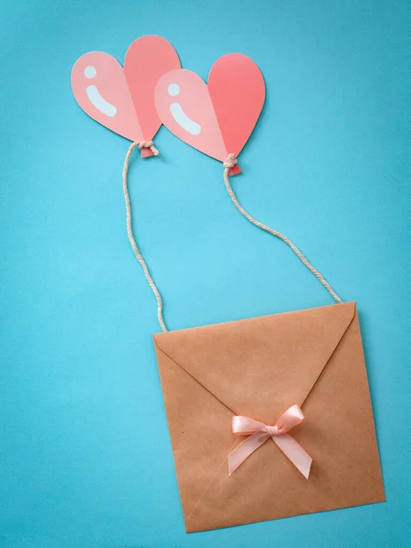 Gefeliciteerd met Valentijnsdag. Een envelop met een hart dat op twee hartvormige ballonnen vliegt is roze. — Stockfoto