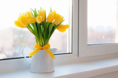 Evin pencere eşiğindeki cam vazoda duran taze sarı laleler..