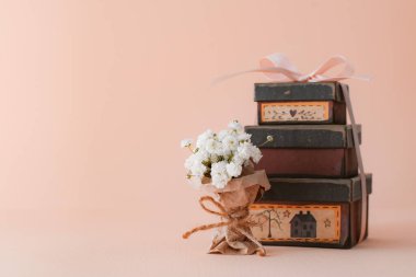 Pembe arka planda klasik dekoratif hediye kutularıyla küçük bir buket beyaz çigila. Doğum günü, kadınlar ya da anneler günü için tebrik kartı.