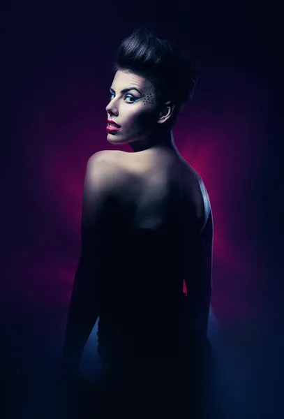 Sexy brunette vrouw met rode lippen in donker magenta licht — Stockfoto
