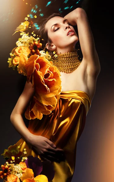 Jolie femme en robe jaune avec des bijoux et des fleurs — Photo