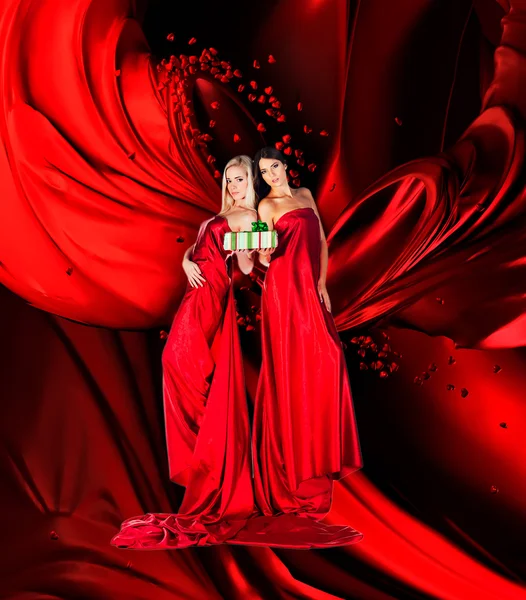 Two women in red dress with present in hands 2 — Stock Photo, Image