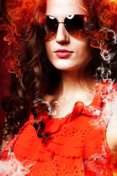 Hot woman in sunglasses in fire and smoke — Stock Photo, Image