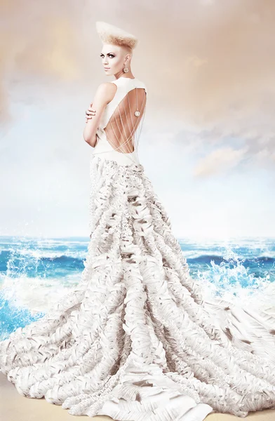 Женщина в длинном белом платье на берегу моря — стоковое фото