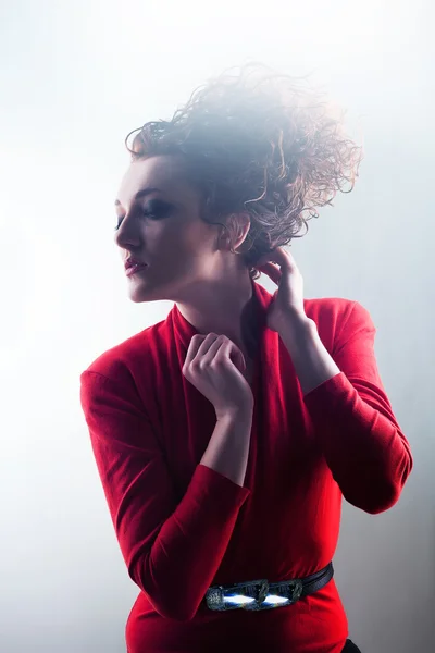 Mulher em vermelho com alto cabelo encaracolado na luz — Fotografia de Stock