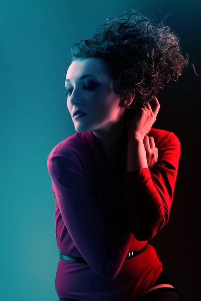 Kırmızılı kadın mavi ışık yüksek kıvırcık saçlı — Stok fotoğraf