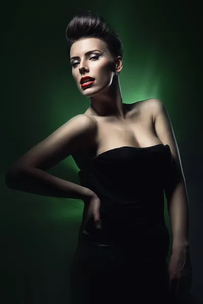 Sexy brunette vrouw met rode lippen in donkere groen licht — Stockfoto
