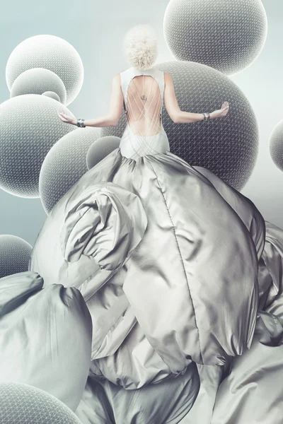 Blond kvinna i lång grå klänning med sfärer — Stockfoto