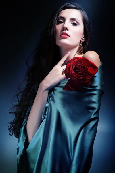 Nainen vihreässä kankaassa punaisella ruusulla — kuvapankkivalokuva