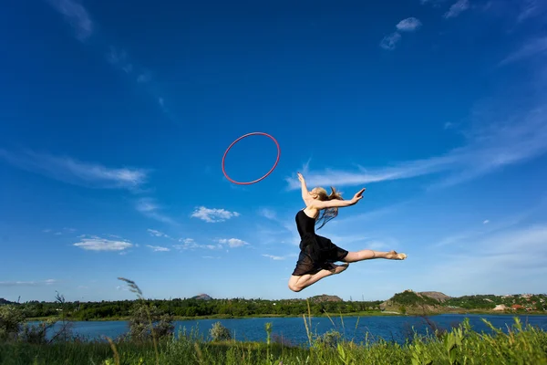 Jymnast met hoepel springen tegen blauwe hemel — Stockfoto