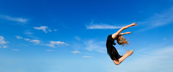 Freedom concept. Dancer jumping against blue sky