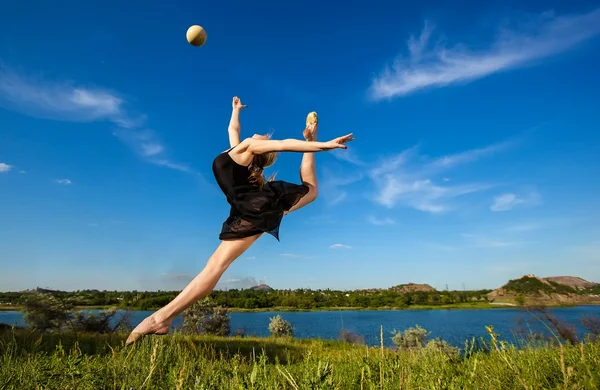 Jonge professionele gymnast springen met bal Stockfoto