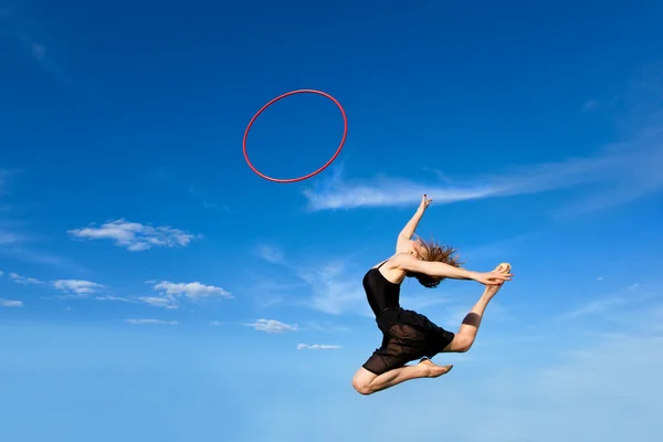 Jymnast met hoepel springen tegen blauwe hemel Rechtenvrije Stockfoto's
