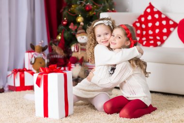 Noel, x-mas, kış, mutluluk kavramı - iki sevimli kıvırcık kız hediye kutusu ile oynama